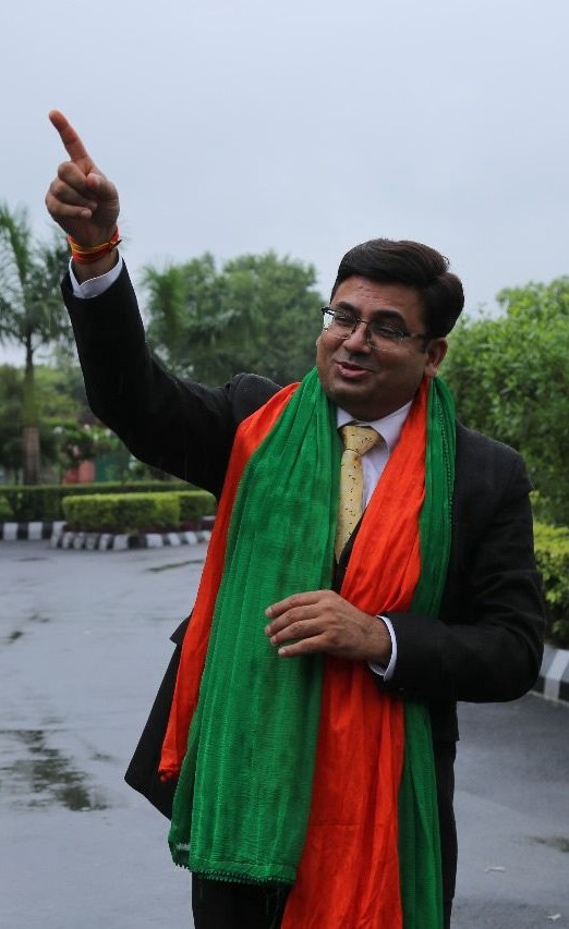 Dr Ajay Rana wearing a tricolor scarf pointing forward outdoors